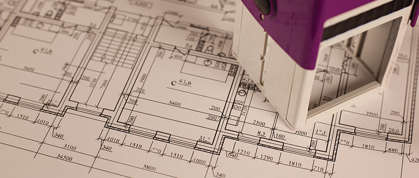 Stamp on plan of house background. Photo © Shutterstock